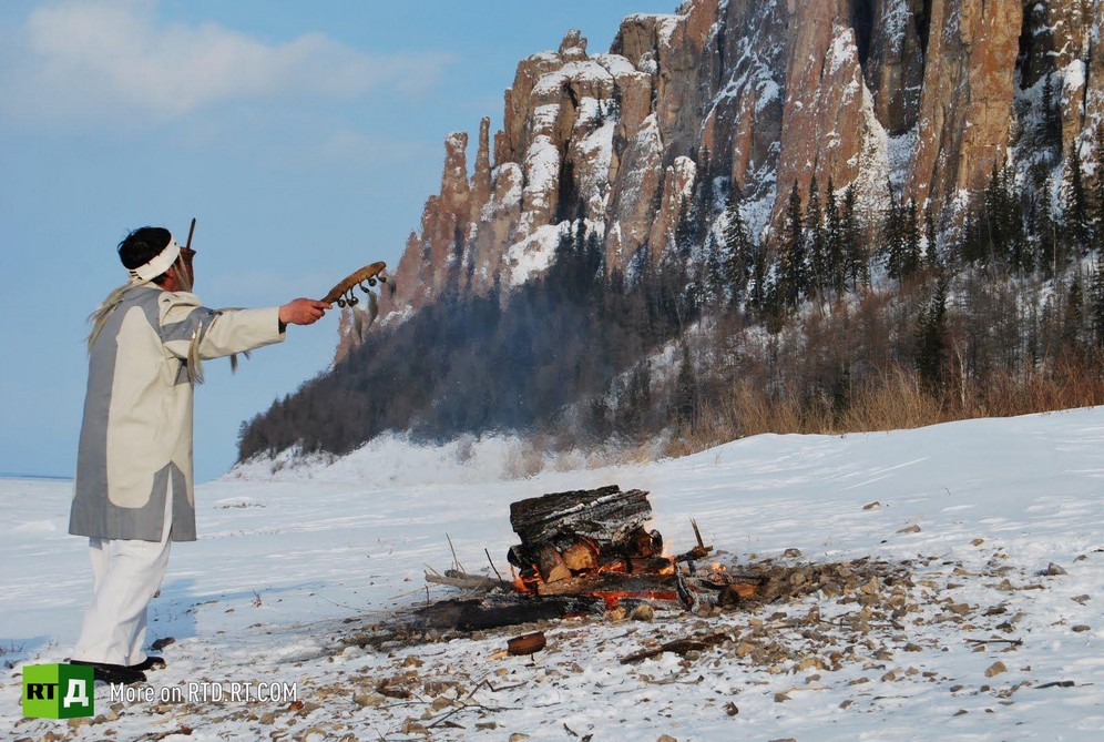 Evenk Shaman performing ritual in front of Lena Pillars, Yakutia, Russia